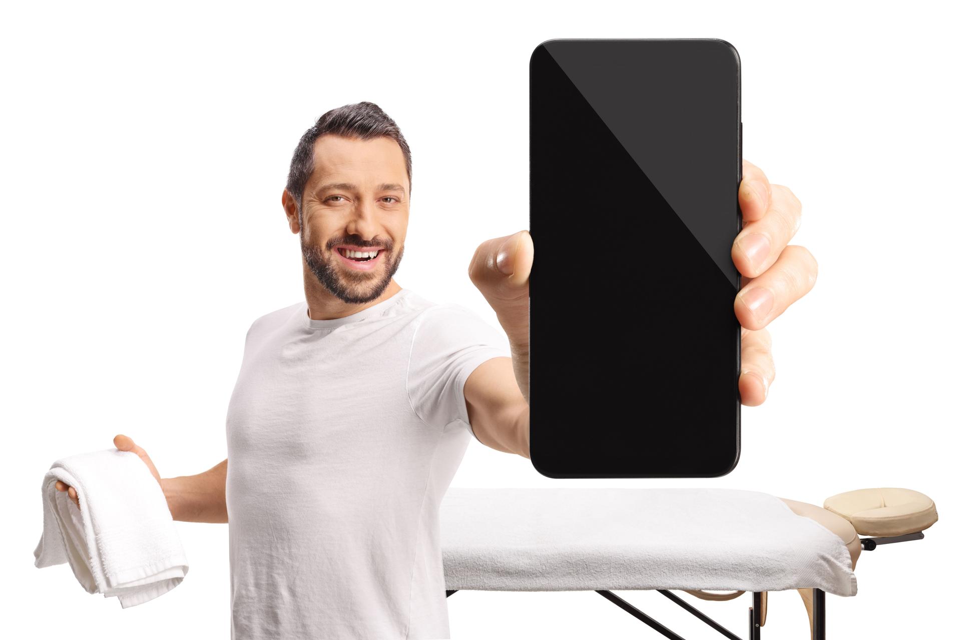Massage therapist holding a smartphone and a towel