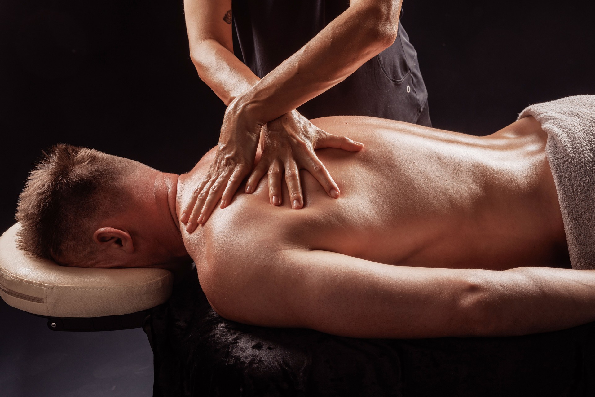 Therapist performing deep tissue back massage using hands for muscle tension relief.